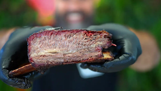 Ready to serve. Smoked beef rib held by Adriano, from his Xtra Mojo recipe video - Secondary view