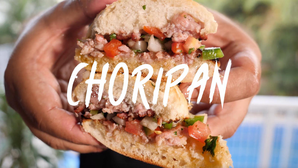 Choripan cut in half, sausage meat pressed onto the bread with a tomato, capsicum and onion salsa