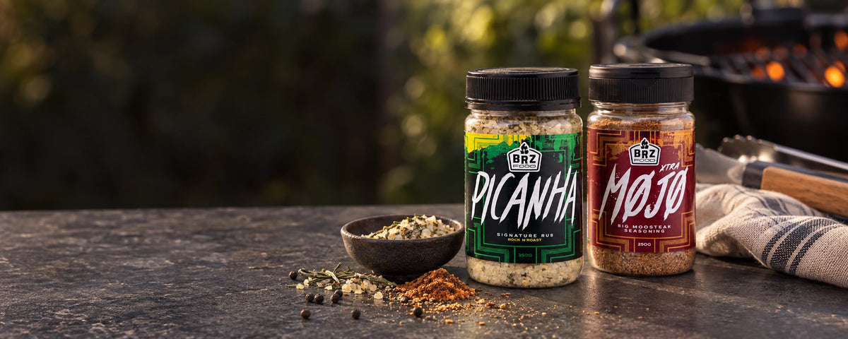 Picanha and Xtra Mojo seasoning jars beside spices on a barbecue preparation bench