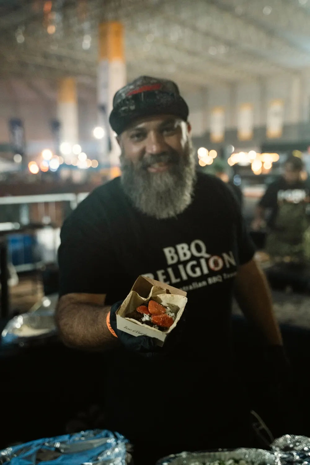 Adriano wearing a BBQ Religion shirt and holding a barbecue dish